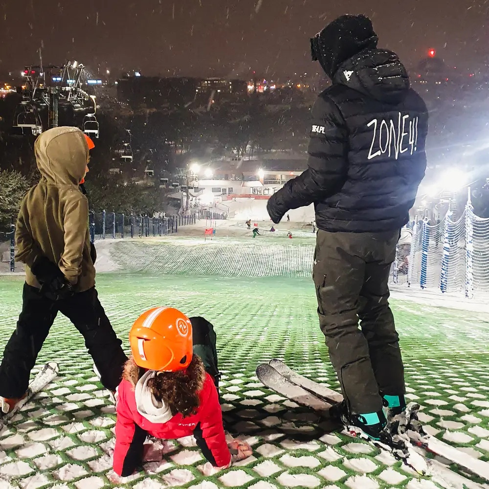 A Zone4 instructor with children on the floodlit Górka Szczęśliwicka slope at night