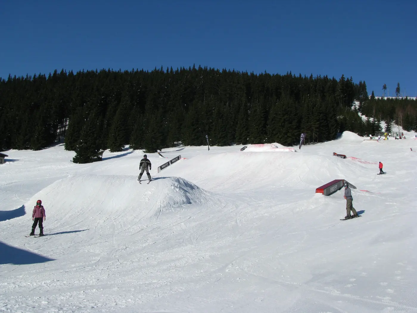 Snowpark na Horních Mísečkach — narciarze i snowboardziści na hopach